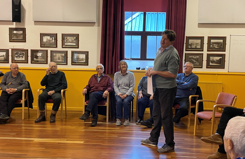 Alex is standing, talking to a ring of seated Positive Steps Kemnay members.