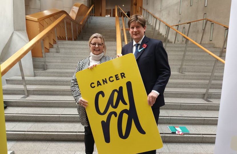 Alex holding a Cancer Card sign; the sign is nearly as tall as he.