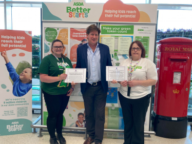 Alex is standing next to two women who are employees of ASDA. Each woman is holding a certificate celebrating the Parliamentary Motions lodged to recognise ASDA.