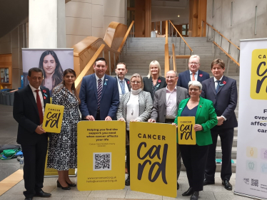 Alex and others from Holyrood posing on a staircase with Cancer Card signage.